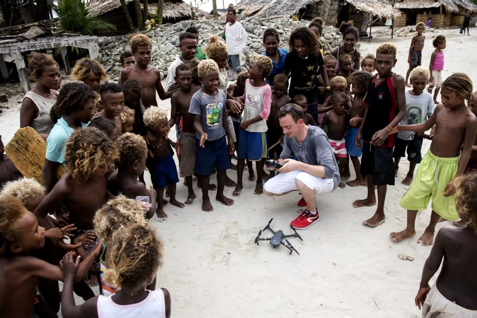 Groupe d'enfants entourant un videaste accroupi devant un drone