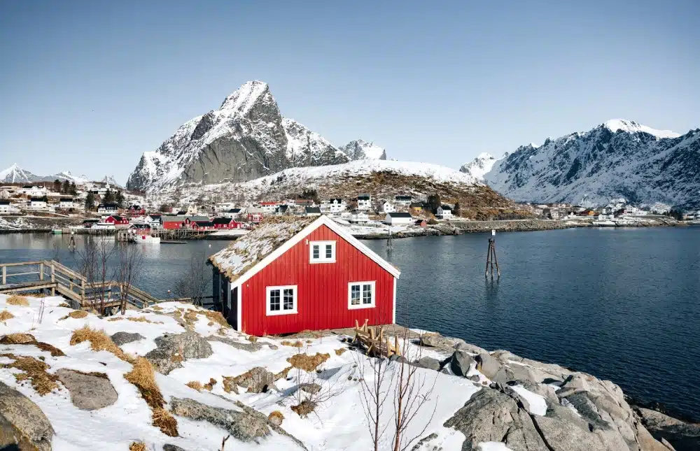 Maison en bois rouge au bord d’un fjord en hiver, Lofoten, Norvège.