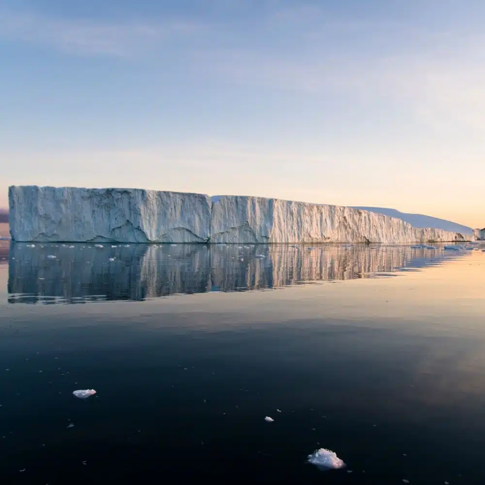 travelling-arctic Raking sunlight touches the sea and an iceberg in Disko Bay, Greenland