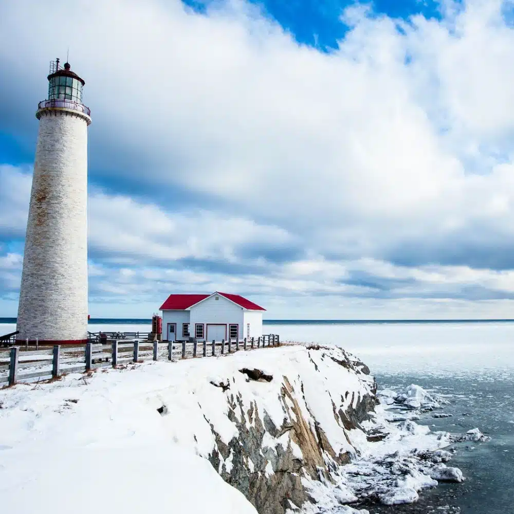 journey-canada Lighthouse and snow-covered cliff, Cap-des-Rosiers in Gaspé, Canada