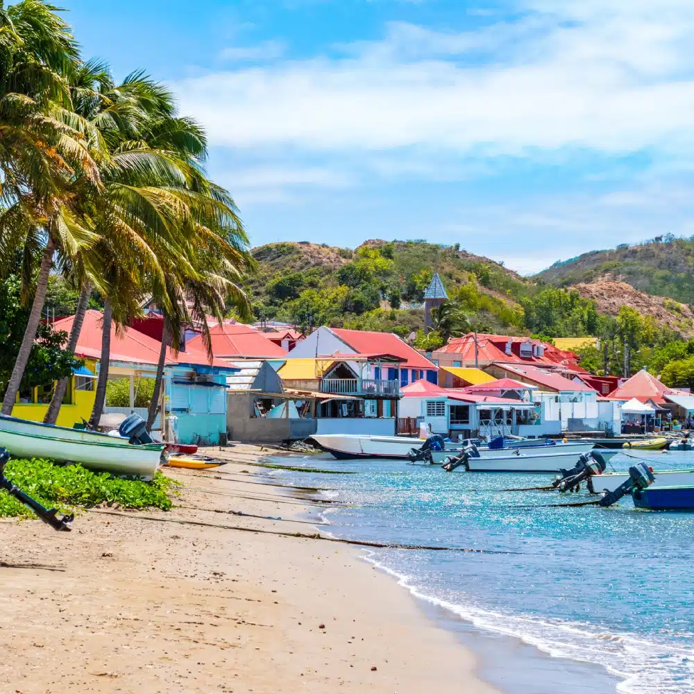 Plage de Terre-de-Haut avec des maisons colorées et des bateaux de pêche amarrés